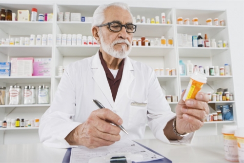 pharmacist looking at a bottle of medicine
